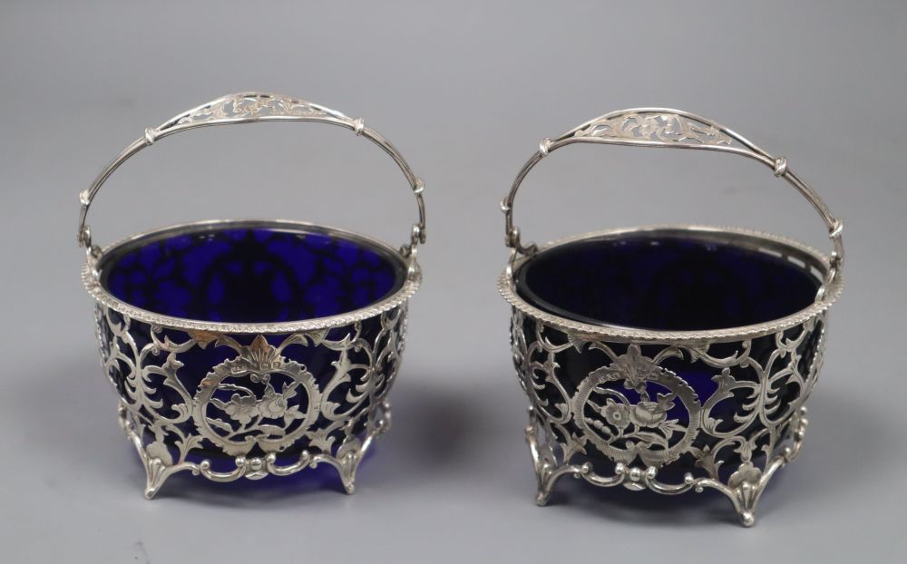 A matched pair of early 20th century pierced silver circular baskets, with blue glass liners